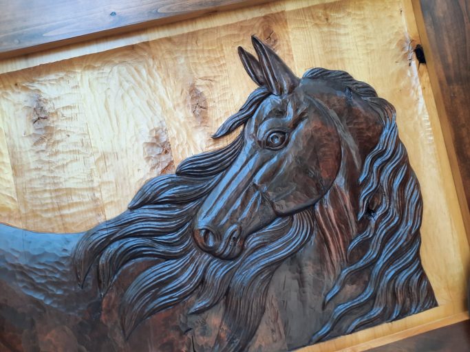 Carved wooden relief of a horse's head with flowing mane.