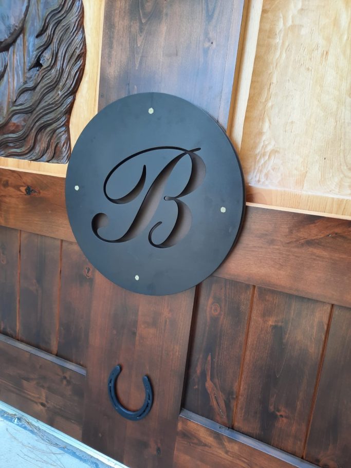 A circular black metal plaque with an ornate letter "B".