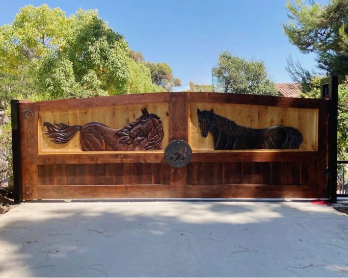 Knotty alder gate featuring carved horses and a circular steel stamp in the center with a plasma cut 'B'. 